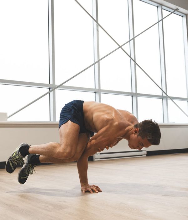 Man performing a controlled strength exercise in a minimalist studio.
